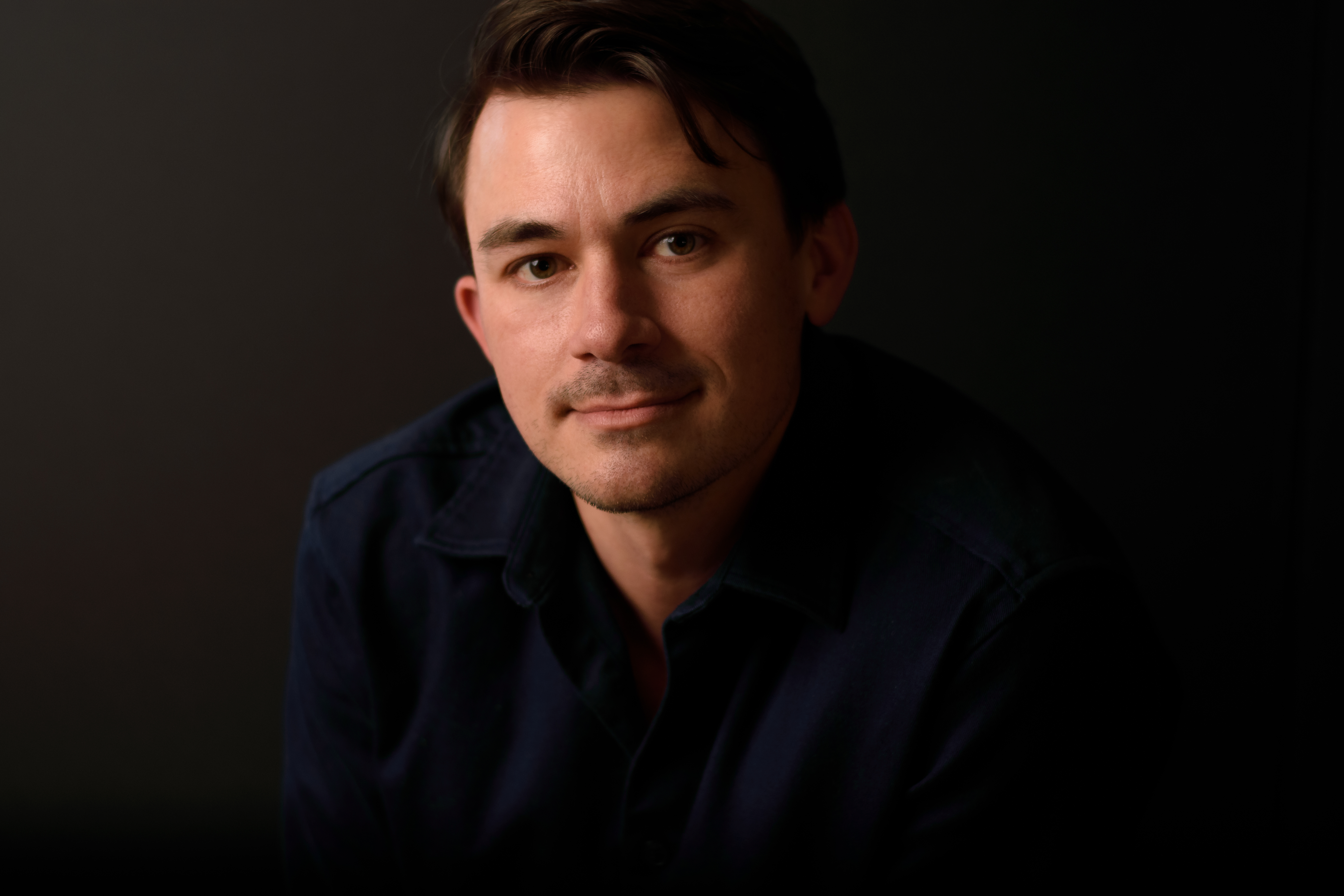 Christian Sanders close-up headshot, dark background